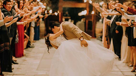 A couple kissing, surrounded by wedding guests