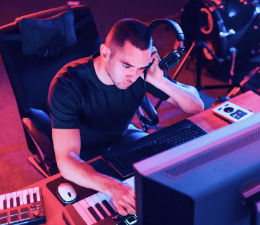 WAV Dateien bearbeiten Mann mit Kopfhörern am Keyboard vor PC