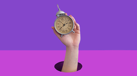 Hand holding up an alarm clock in front of a purple background