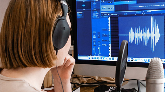 Mulher gravando e editando o áudio do seu vídeo para apresentar a normalização do som em vídeos