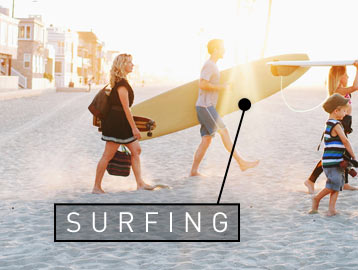 Glückliche Familie mit Surfbrettern am Strand bei Sonnenaufgang
